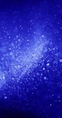 Mavi zemin üzerinde hareket eden parçacıkların dikey yönelimi. Parçacıklar beyaz ve boyut olarak çeşitlidir, bokeh veya yüzen toza benzerler.