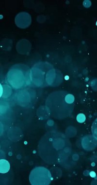 Çoğunluğu turkuaz olan parlayan parçacıklar yağmuru koyu bir arkaplana doğru yükselir. Parçacıkların boyutları ve yoğunluğu farklıdır, daha büyükleri bulanık ve bulanık görünür.