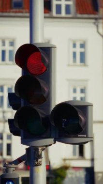 Yakın çekim görüntüsü, trafik akışını izlemek veya yönetmelikleri uygulamak için kullanılan yakın bir trafik kamerası veya sensör ile kırmızıdan yeşile geçiş yapan metalik bir direğe monte edilmiş bir trafik ışığını gösterir.