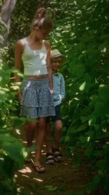 İki rahat ve mutlu kardeş, yoğun yeşilliklerle dolu yemyeşil bir alanda el ele yürüyorlar. Beyaz atlet bluzlu ablası, mavi desenli etekli ve sandaletli.