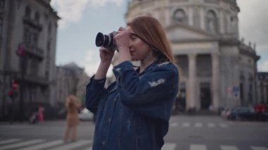 Frederik Kilisesi 'nin yakınlarındaki caddelerde yürüyen bir kadın turist kamerasıyla etrafındaki binaların çarpıcı fotoğraflarını çekiyor.