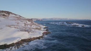 Hava manzarası engebeli, karla kaplı adaları engin bir okyanusun ortasında açık mavi bir gökyüzünün altında yakalıyor.