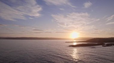 Norveç denizleri üzerinde nefes kesici bir dron uçuşu batan güneşleri yakalayarak suların yüzeyinde büyüleyici bir parıltı oluşturur ve gölgeli adaların altın ışıkla yıkanmış huzur dolu güzelliklerini gözler önüne serer.