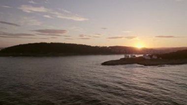 Langoytangen Deniz fenerini ve Norveç kıyı evlerinin üzerinde çarpıcı bir günbatımını yakalayan hava aracı görüntüsü