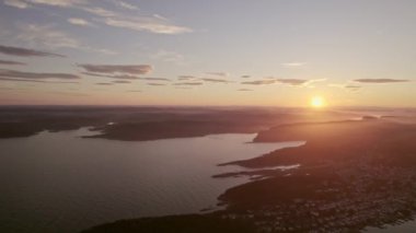 Gün batımında Norveç 'teki resimli rıhtım ve siluetli adaları yakalayan geri çekilen bir insansız hava aracı.