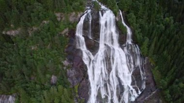 Büyüleyici bir hava görüntüsü Furebergsfossen Şelalesi 'nin ihtişamını yakalar ve gür yeşil çam ormanlarıyla çevrili engebeli kayalıklardan aşağı düşen çağlayan suyu gösterir.