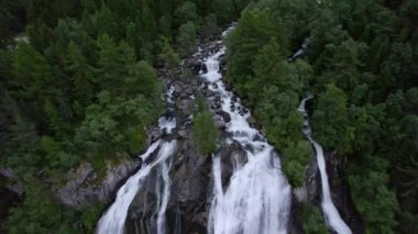 Furebergsfossen şelalesinin engebeli kayaların üzerinde şelaleden düşüşü güçlü su akışını ve çevreleyen doğal manzarayı gözler önüne seriyor.