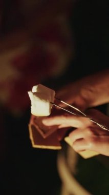 Kapalı el kameraları açık havada şekerleme hazırlarken, marşmelovlar bir kamp ateşinde kızartılıyor.