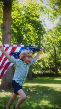 Gün boyunca yeşil çimlerin üzerinde Amerikan bayrağıyla koşan sevimli çocuk neşeli ve vatansever bir anı yakalıyor.
