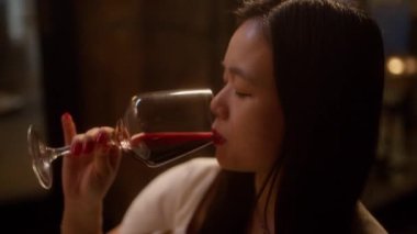 Bir kadının şarap yudumlarken gelişigüzel konuştuğu yakın plan görüntüsü.