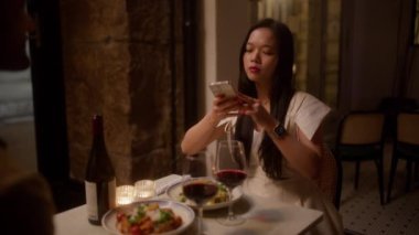 Güzel bayan yemeğinin fotoğraflarını çekiyor ve flörtüne ne poz vereceği konusunda talimatlar veriyor.