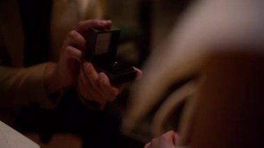 Yakın plan, romantik bir akşam yemeği teklifinden sonra parmağına bir nişan yüzüğü takıldığını gösteriyor. Samimi ve kutlama anını yakalıyor.