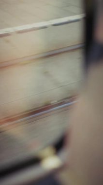 Hareket halindeki bir trenin penceresinden gelen bulanık bir görüntü, ön plandaki çerçevenin kenarını ve kaldırım, çimen ve aşağıdaki raylarla hızla geçen bir manzarayı gözler önüne serer ve bir hız hissi yaratır.