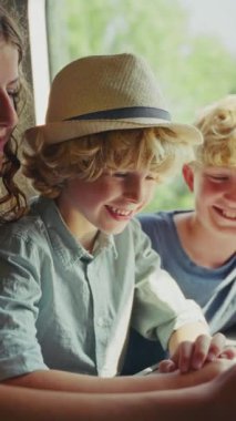 Kardeşler yan yana otururlar, cep telefonuna dalmış bir şekilde, pencerelerden süzülen güneş ışığıyla sorunsuz bir şekilde süzülen bir trende seyahat ederler.