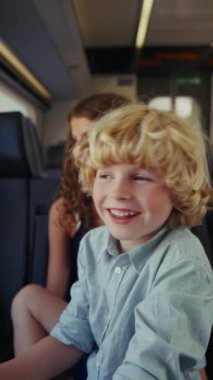 Bir çocuk tren yolculuğu sırasında bir şeye bakarken mutlu bir şekilde gülümser. Manzara geçerken bir neşe ve merak anı yakalar.