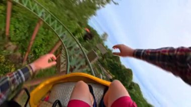 Sarı bir roller coaster 'ın heyecan verici ön koltuğu doğal bir manzarada yarışıyor, heyecanı ve manzaralı güzelliği yakalıyor.