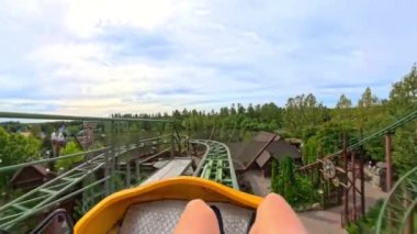Ağaçlarla ve yeşilliklerle dolu bir lunapark treninin manzarası uzaktan arka plan görevi görüyor.