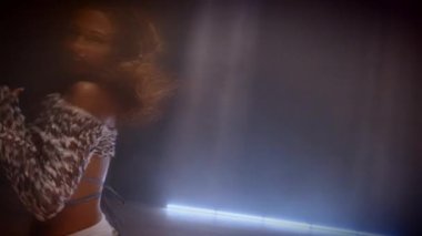 Yetenekli bir bayan dansçı, çarpıcı ışın ışıklarıyla aydınlatılmış bir stüdyoda dinamik bir hip hop dansı solosu sergiliyor.