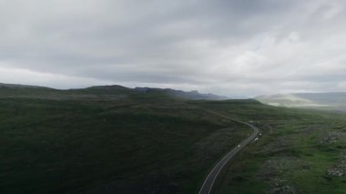 Yumuşak bir sabah sisi ve bulutlu gökyüzü manzaraya rüya gibi bir hava katarken, yeşil tepelerin arasından huzurlu bir yol uzanıyor.