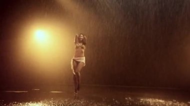 Bir dansçı, arka planda çarpıcı turuncu ışıklarla aydınlatılan kuvvetli bir performans sergiliyor ve büyüleyici ve dinamik bir görsel etki yaratıyor.