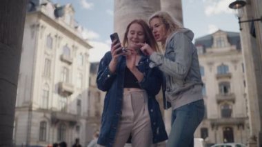 Frederik 'in kilisesinin önünde duran iki arkadaş, ziyaretteki fotoğraflarını gözden geçirirken bir akıllı telefonun etrafında toplandılar.