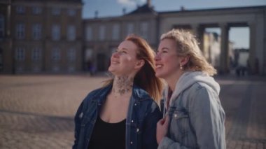 Kopenhag 'daki Amalienborg Sarayı' nın manzaralı görüntüsünü alan iki turistin orta ölçekli yakın çekimi.