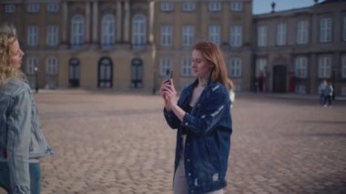 Bir kadın, arkaplan görevi gören görkemli Amalienborg Sarayı 'yla arkadaşının fotoğrafını çekiyor.