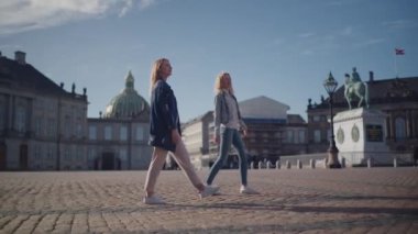 Amalienborg 'un kaldırım taşları üzerinde yürüyen iki kadın, tarihi bölgeyi rahatça keşfediyorlar.