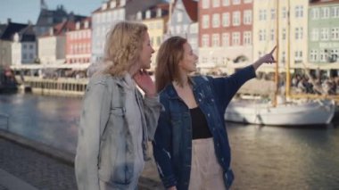 Nyhavn 'ın resimli liman bölgesinde boş boş gezinen iki kadın manzaranın tadını çıkarıyor.