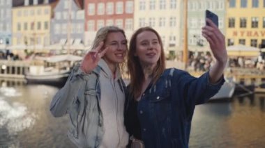 İki kadın, Kopenhag 'daki Nyhavn' un ikonik turistik yerine selfie çekerek seyahat hatıralarını yaratıyor.