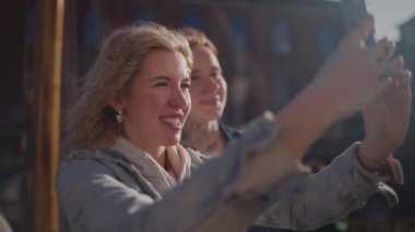 Turistler Nyhavn, Kopenhag 'da parlak güneş ışığı altında selfie çekerek ikonik liman bölgesinin canlı atmosferini yakalıyorlar.