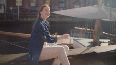 Mutlu bir gezgin Kopenhag 'daki ikonik Nyhavn Kanalı' nda poz veriyor. Etrafı renkli tarihi binalar ve canlı kanal tekneleriyle çevrili.