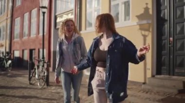 İki turist heyecanlı bir şekilde Nyhavn 'un canlı ve renkli binalarının arasında koşuyor, neşeli atmosferi yakalıyorlar.