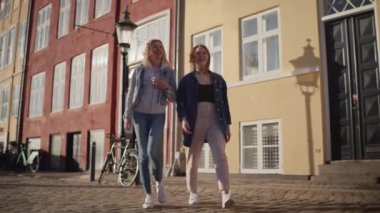 Gezginler Nyhavns 'ın ikonik renkli binalarında yürüyor, canlı atmosferi ve tarihi cazibeyi yakalıyorlar.