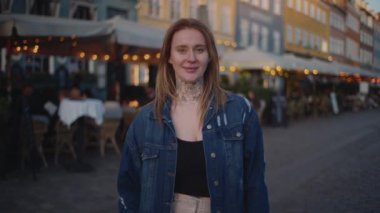 Bir zoom çekimi Nyhavn 'un renkli binalarına karşı bir turisti, açık hava şemsiyelerinden gelen bokeh ışıklarıyla yakalıyor.