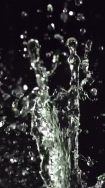 Karmaşık su damlacıklarının büyüleyici bir yavaş çekim görüntüsü düşüyor ve çarpışıyor, narin şekillerini ve titreyen yansımalarını sergiliyorlar.