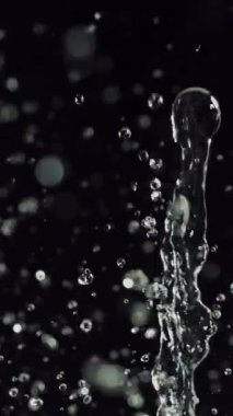 Su sıçrayan ve yavaşça koyu bir zemine düşen sinematik görüntüler, hareket halindeki sıvının güzelliğini ve akıcılığını vurguluyor.