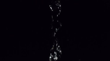 Bu durgun, yavaş çekim sekansında, kristal berrak su akışı siyah bir arkaplana doğru aşağı doğru akmaktadır.