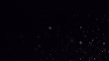 Büyüleyici yavaş çekim su sıçraması. Titreyen bokeh parçacıklarının arkaplanına damlacıklar sıçrıyor. Rüya gibi ve zarif bir atmosfer yaratıyor.