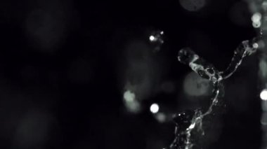 A mesmerizing slow-motion water splash surrounded by shimmering bokeh particles that create a captivating and enchanting ambiance