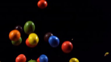 Tatlı yuvarlak şekerler zıplar ve ağır çekimde çatlar, canlı renkler sergiler ve yüzeye çıktıklarında büyüleyici dokular sergilerler.