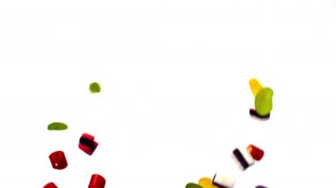 Renkli şekerler, parlak beyaz bir arkaplan karşısında yavaşça havada süzülür. Canlı ve büyüleyici bir görsel manzara yaratır.