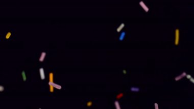 Siyah bir arkaplana karşı yavaş çekimde renkli serpintiler büyüleyici ve canlı bir görsel ekran oluşturur.