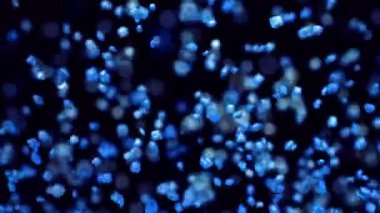 Karanlık bir arkaplana karşı yumuşak dairesel bokeh parçacıkları ile canlı mavi serpiştirilmiş büyüleyici yavaş hareket