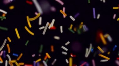 Canlı bir tatlı serpiştirme dizisi zarif bir şekilde siyah bir zemine doğru süzülür, görsel olarak büyüleyici ve şenlikli bir görüntü yaratır.