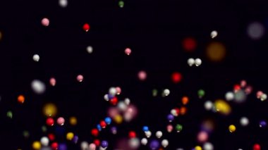 Renkli yuvarlak serpintiler yavaş çekimde zarifçe sürükleniyor, karanlık bir arka plana karşı neşeli ve canlı bir görsel zevk yaratıyor.