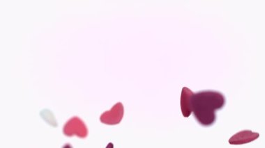 Kalp şeklinde serpintiler, beyaz bir arkaplana karşı yavaşça havada süzülür.