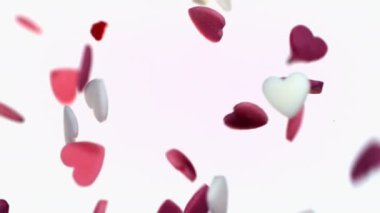 Renkli kalp şeklinde serpintiler beyaz bir arkaplan üzerinde nazikçe süzülüyor, kaprisli ve neşeli bir görsel yaratıyor.