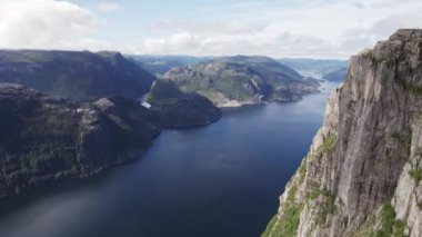 Drone görüntüsü, Norveç 'in görkemli dağlarından akan dolambaçlı bir nehri dramatik, bulutlu bir gökyüzünün altında yakalıyor.