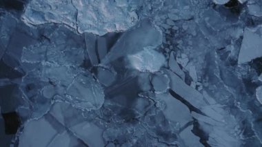 Denizin engin yüzeyinin yukarıdan çekimleri düzensiz yamalar ve soğuk sularını kaplayan buz parçalarıyla dağılmış.